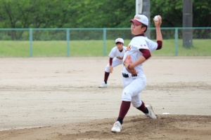 グラウンドでユニフォームを着た生徒がピッチングをしている写真