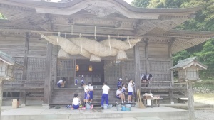 神社の境内で児童たちが清掃活動をしている写真