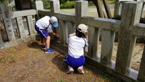 神社の石垣を児童たちが掃除している写真