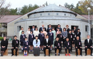 校舎前の階段で新入生と教職員が並んで記念撮影をしている写真