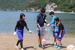 海岸で生徒たちがゴミ拾い活動を行っている写真