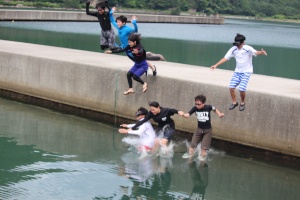 防波堤にいる生徒たちが海に飛び込む様子の写真