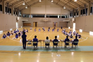 体育館で生徒たちが円形に座り会議形式で話し合っている写真