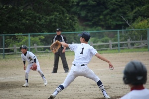 グラウンドでユニフォームを着た生徒がピッチャーとして投球している写真