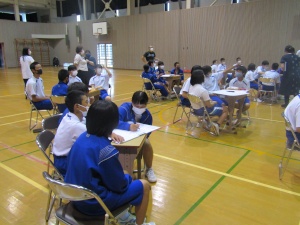 体育館でジャージを着た生徒たちがグループに分かれて話し合いしている写真