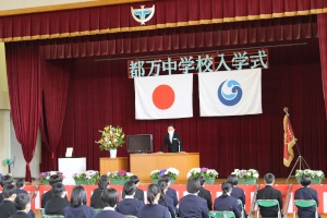 体育館の壇上で校長先生が入学式の式辞を述べている写真