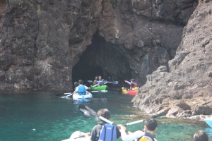 岩場の洞窟に向かってカヤックで進む生徒たちの写真