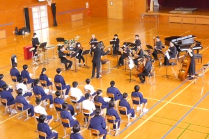 体育館で演奏会を鑑賞する生徒たちの写真