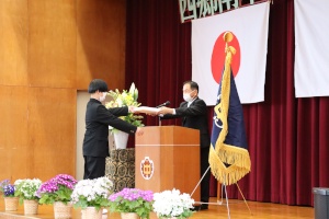 壇上で校長先生が生徒に入学証書を手渡している写真