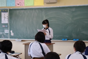 教室で女子生徒が前に立って発表している写真