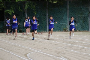 校庭のトラックで生徒たちが短距離走を競っている写真