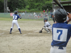 グラウンドで少年野球の選手が打席に立ち試合に臨んでいる写真