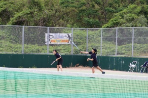 テニスコートで生徒たちがダブルスの試合をしている写真