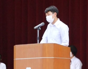 壇上で男子生徒がマイクの前でスピーチをしている写真