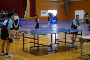 体育館で卓球をするユニフォームを着た男子生徒2人の写真