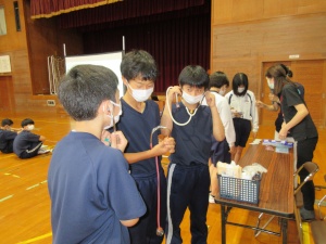 体育館で聴診器を使い体験学習をする生徒たちの写真