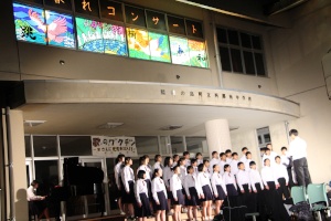 昇降口前で催された夕暮れコンサートで整列して合唱する生徒たちの写真