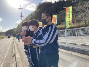 マスクをして沿道に立ち、拍手をしながら駅伝の応援をしている生徒たちの写真