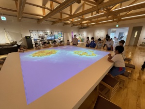 展示施設で地図の映像を見学する児童たちの写真