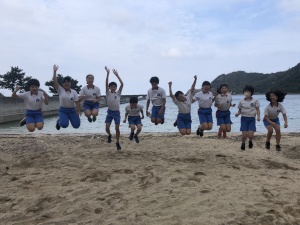 砂浜でジャンプしてはしゃぐ児童たちの写真