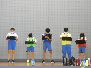 体育館で試合の記録をつける児童たちの写真