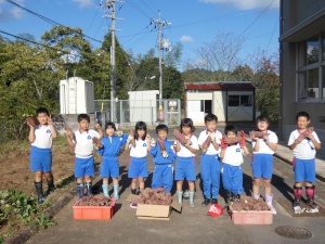 学校の畑でサツマイモを収穫する児童たちの写真