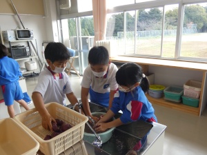 家庭科室でサツマイモを洗う児童たちの写真