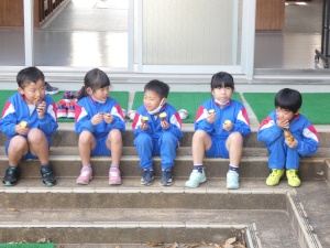 校舎の前で焼きいもを食べる児童たちの写真