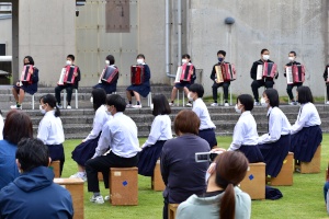 校庭で生徒たちがアコーディオン演奏を披露する様子の写真
