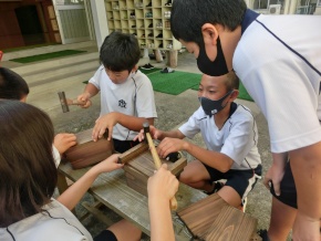 校庭で児童たちが協力して巣箱を作っている写真