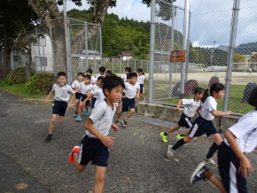 校庭で外周を走る児童たちの写真