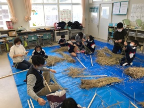 教室で児童たちが藁を使って工作をしている写真