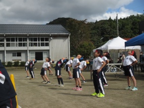 校庭で体操をして準備運動をする児童たちの写真