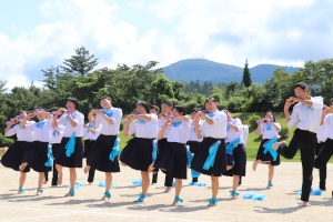 校庭で青いはちまきをつけた生徒たちがダンスを披露している写真