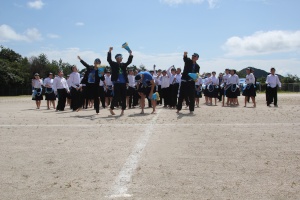 運動場で青い衣装の生徒たちが踊る写真