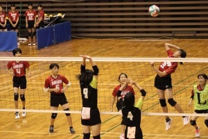 体育館で女子バレーボールの試合をする写真
