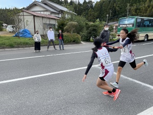 駅伝で女子生徒がタスキを渡す瞬間の写真