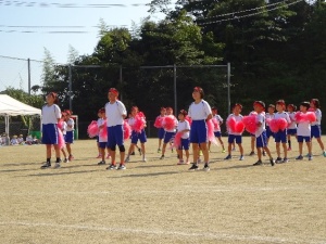 運動場で赤組が応援ダンスを披露している写真