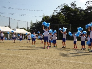 運動場で青組がポンポンを振って踊っている写真