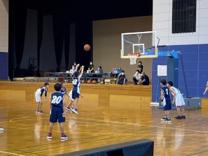 体育館でバスケットボールの試合をする児童たちの写真