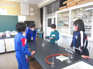 理科室で生徒たちが実験の説明を聞いている写真