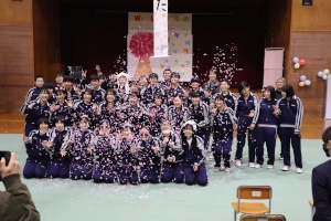 体育館で卒業生たちが記念撮影をする写真