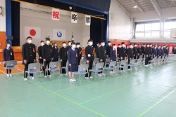 体育館で3列になって横に並んで立ち、卒業式に参加する生徒たちの写真