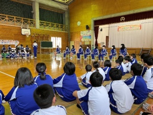 体育館で「6年生を送る会」に参加する体操着姿の児童たちの写真