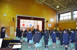 体育館で少し緊張した様子で卒業式に参加する制服姿の児童たちの写真