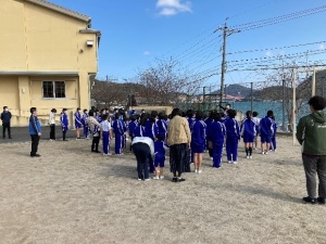 校庭で整列して話を聞く体操着姿の児童たちの写真