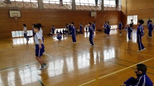 体育館で体操着姿の児童たちが適切な間隔を保ちながら縄跳びをしている写真