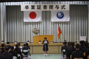 卒業式で座っている生徒たちの前で代表者がマイクの前に立っている写真