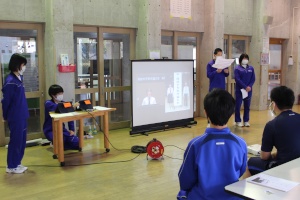 体育館で生徒たちが新入生にプロジェクターを使用して説明をしている写真