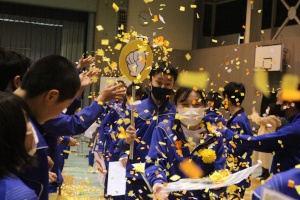 体育館で生徒たちが黄色い紙吹雪に包まれている写真